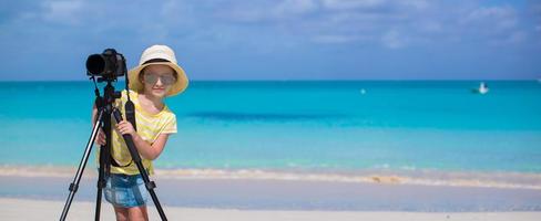 petite fille prenant des photos avec un appareil photo sur un trépied pendant ses vacances d'été