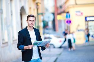 homme touriste avec un plan de la ville et un sac à dos dans la rue de l'europe. garçon caucasien regardant avec la carte de la ville européenne. photo