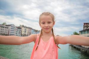 adorable petite fille prenant un selfie à l'extérieur à zurich, en suisse. closeup portrait d'enfant fond de belle ville photo