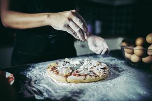 mains du chef, verser la farine sur la pâte crue photo