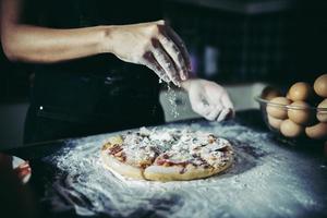 mains du chef, verser la farine sur la pâte crue photo