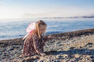 adorable petite fille jouant sur la plage dans une journée ensoleillée d'hiver photo