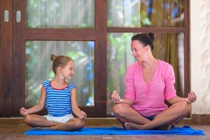 jeune femme et petite fille faisant des exercices de yoga en plein air sur la terrasse photo