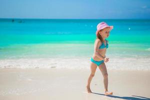 jolie petite fille jouant dans l'eau peu profonde à la plage exotique photo