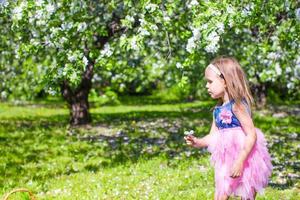 adorable petite fille s'amuse dans un jardin de pommiers en fleurs en mai photo