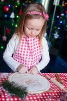 adorable petite fille préparant des biscuits au pain d'épice pour noël à la cuisine photo