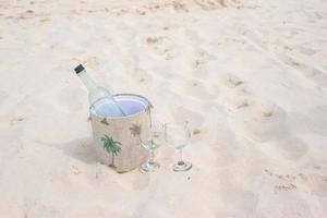 bouteille de vin et deux verres sur la plage de sable photo