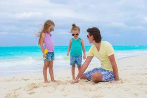 adorables petites filles et papa heureux sur la plage blanche tropicale photo