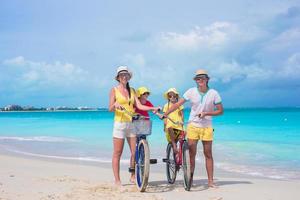 jeune famille avec de petits enfants faire du vélo sur la plage tropicale photo