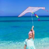 petite fille heureuse jouant avec un cerf-volant sur une plage tropicale photo