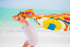 jolie petite fille s'amusant à courir avec un paréo sur une plage tropicale photo