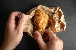 Mains ramasser du poulet frit croustillant sur papier brun photo