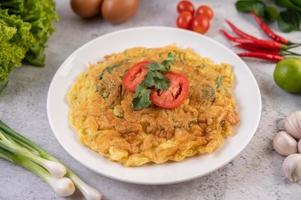 Omelette aux œufs sur une assiette blanche avec des tomates photo