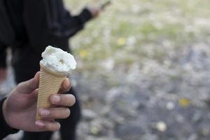 gros plan d'une main et d'un cornet de crème glacée photo