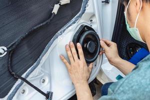 mécanicien installant le haut-parleur sur la porte du véhicule dans le garage photo