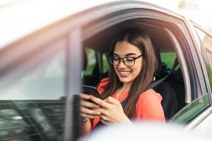 envoyer des SMS et conduire, derrière le volant. enfreindre la loi. femme au volant d'une voiture distraite par son téléphone portable. femme tapant un message au téléphone en attendant dans la voiture. photo