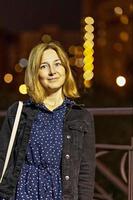 portrait d'une jeune femme dans une ville nocturne un soir d'été. lumières de la ville photo