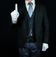 portrait de majordome en costume sombre sur fond noir dans des gants blancs propres. concept d'industrie de services et d'hospitalité professionnelle. photo