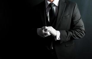 portrait de majordome en costume sombre et gants blancs désireux de rendre service. concept d'hospitalité et de courtoisie professionnelles. photo