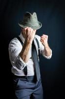 portrait d'homme d'affaires en chemise blanche et vieux chapeau fedora avec les poings levés prêts à se battre. style vintage et mode rétro du détective de film noir ou du combattant du crime. photo