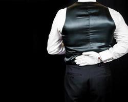 portrait de majordome ou serveur en gants blancs et gilet noir debout avec la main derrière le dos. concept élégant de l'industrie hôtelière. photo
