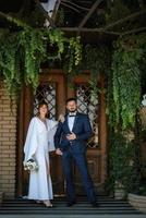 mariée en robe blanche avec un bouquet et le marié en costume bleu photo