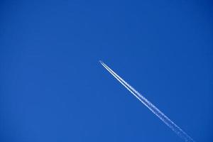 les pistes d'avion suivent les chemtrails dans le ciel bleu profond photo