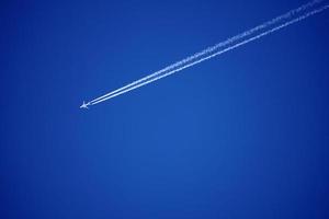 les pistes d'avion suivent les chemtrails dans le ciel bleu profond photo