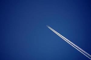 les pistes d'avion suivent les chemtrails dans le ciel bleu profond photo