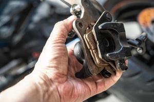 le mécanicien remplace et ajuste le système de freinage de la moto, la plaquette de frein. entretien, réparation du concept de moto dans le garage. mise au point sélective photo