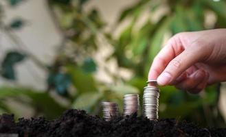 la main de la femme met des pièces d'argent sur une pile de pièces d'argent avec un fond de nature verdoyante. concept d'économie d'argent et de financement des entreprises, croissance des entreprises et avenir de l'argent, succès financier photo