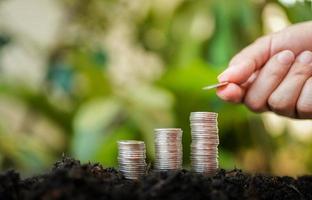 la main de la femme met des pièces d'argent sur une pile de pièces d'argent avec un fond de nature verdoyante. concept d'économie d'argent et de financement des entreprises, croissance des entreprises et avenir de l'argent, succès financier photo