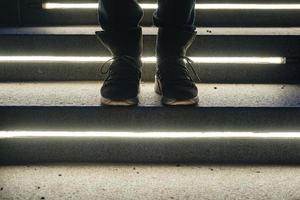 des jambes féminines en bottes en daim se tiennent sur les marches de pierre illuminées un soir d'hiver. photo