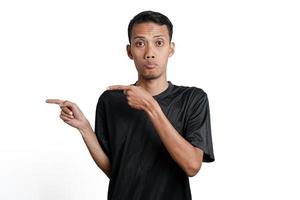 homme asiatique excité portant un t-shirt d'entraînement noir, pointant vers l'espace de copie. isolé sur fond blanc photo