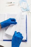 la main d'un médecin dans des gants bleus se prépare à la vaccination. coronavirus, vaccination covid-19. table de travail du médecin. photo