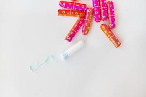 tampon médical féminin dans un emballage rose et orange sur fond blanc. tampon blanc hygiénique pour femme. coton-tige. menstruations, contraception. photo