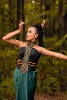 belles danseuses indonésiennes avec des costumes verts traditionnels et des cheveux noirs attachés posant à l'intérieur de la forêt photo