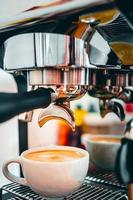 extraction de café de la machine à café avec un porte-filtre versant du café dans une tasse, expresso poruing de la machine à café au café photo