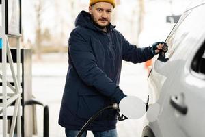 homme faisant le plein de sa voiture suv américaine à la station-service par temps froid. photo