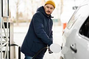 homme faisant le plein de sa voiture suv américaine à la station-service par temps froid. photo