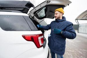 l'homme essuie le coffre de la voiture suv américaine avec un chiffon en microfibre après le lavage par temps froid. photo