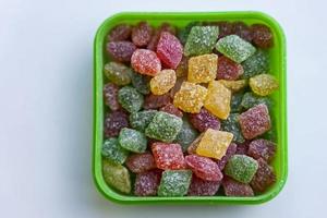 sucettes multicolores de montpensier dans une boîte sur fond blanc, bonbons sucrés photo