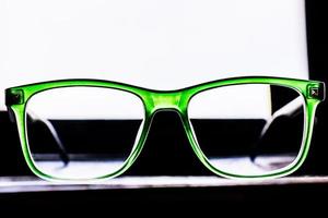 verres devant la fenêtre. lunettes pour la correction de la vue dans un cadre vert. photo