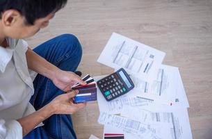 l'homme asiatique est stressé par les problèmes financiers. avec des factures et diverses factures et calculatrices placées tout en ayant des problèmes avec les dépenses de la maison. notion de dette photo