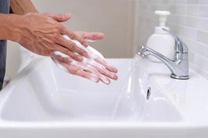 les mains de la personne se lavent avec des bulles de savon et rincent à l'eau claire pour prévenir et arrêter la propagation des germes, virus ou covid-19. bonne santé et bonne hygiène photo