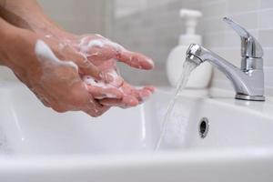 les mains de la personne se lavent avec des bulles de savon et rincent à l'eau claire pour prévenir et arrêter la propagation des germes, virus ou covid-19. bonne santé et bonne hygiène photo