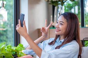 de belles et mignonnes femmes asiatiques utilisent le téléphone pour prendre un selfie. les femmes sont heureuses et aiment prendre des photos. la détente d'une femme de 20 à 30 ans photo