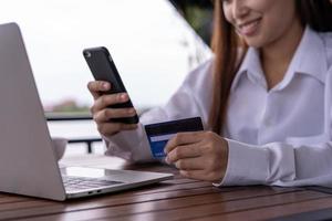 gros plan des mains féminines tenant une carte de crédit et un smartphone. femme payant en ligne, utilisant un service bancaire, saisissant des informations, payant des factures, concept de shopping. photo