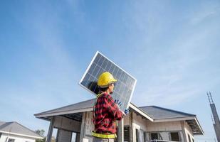 des techniciens transportant des panneaux solaires prêts à être installés sur le toit d'un lotissement concept d'économie d'énergie et de coûts possèdent une petite entreprise d'installation de panneaux solaires. photo