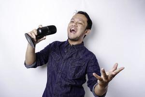 portrait d'un homme asiatique insouciant, s'amusant au karaoké, chantant au microphone en se tenant debout sur fond blanc photo